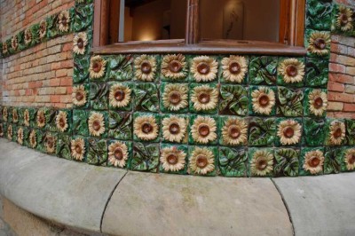 DSC_1220 Sonnenblumen.JPG (141.11 KiB) 9158 mal betrachtet Auffällig ist die Gestaltung des Gebäudes mit einer Vielzahl von Sonnenblumenmustern, die in horizontalen Streifen entlang der gesamten Fassade und dem zylindrischen Turm, der sich über dem Portikus des Eingangs erhebt, angeordnet sind.