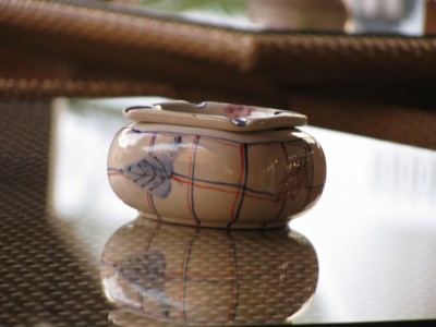 Aschenbecher auf einem mit Glas bedecktem Rattan-Tisch